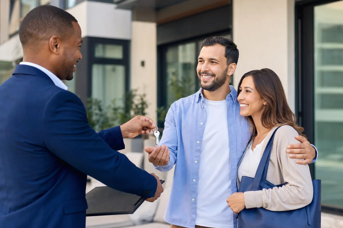 Landlord handing over keys to happy new tenants after completing a tenant background check